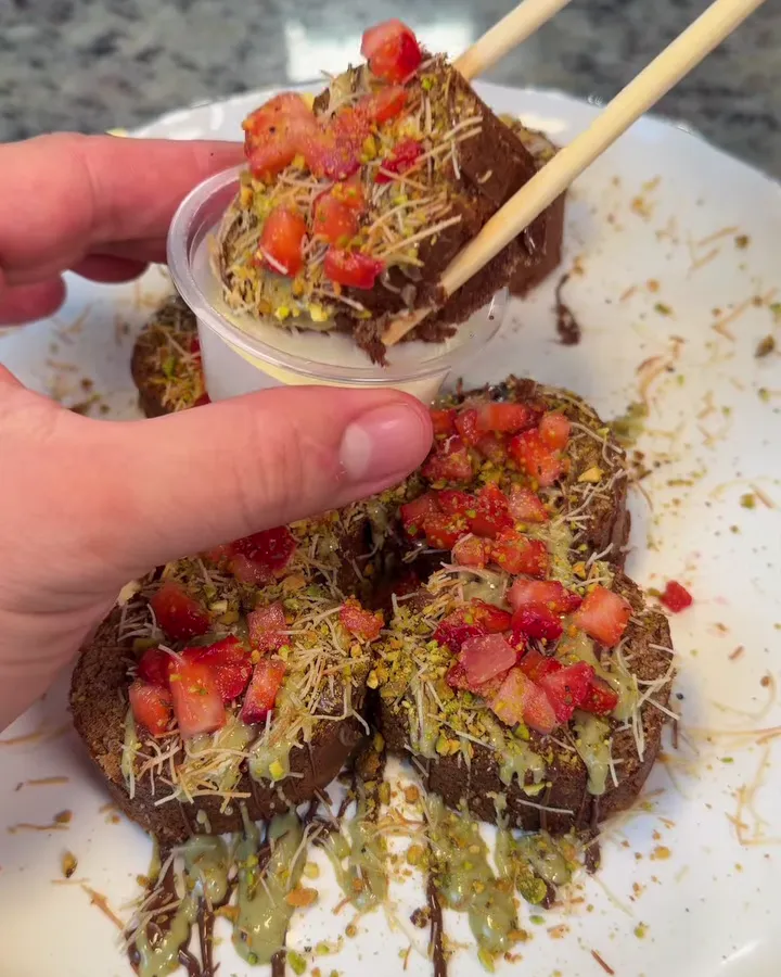 Una pieza de Dubai Roll mojada en crema con palillos